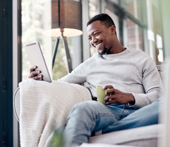 A man smiling and looking at a tablet